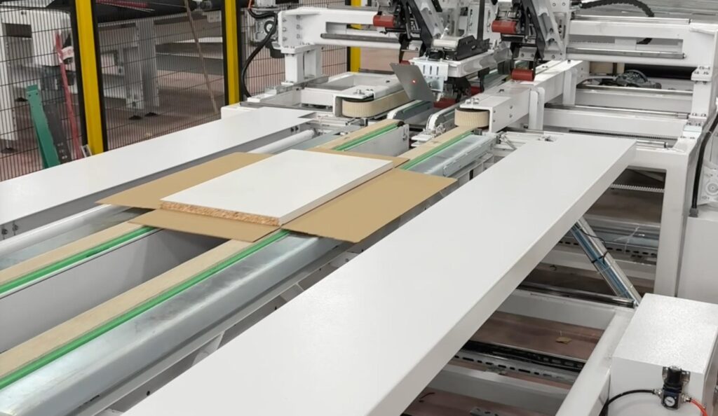 A disassembled furniture panel positioned automatically on an open Fefco 0401 cardboard box inside the Edda Lotis packaging line.