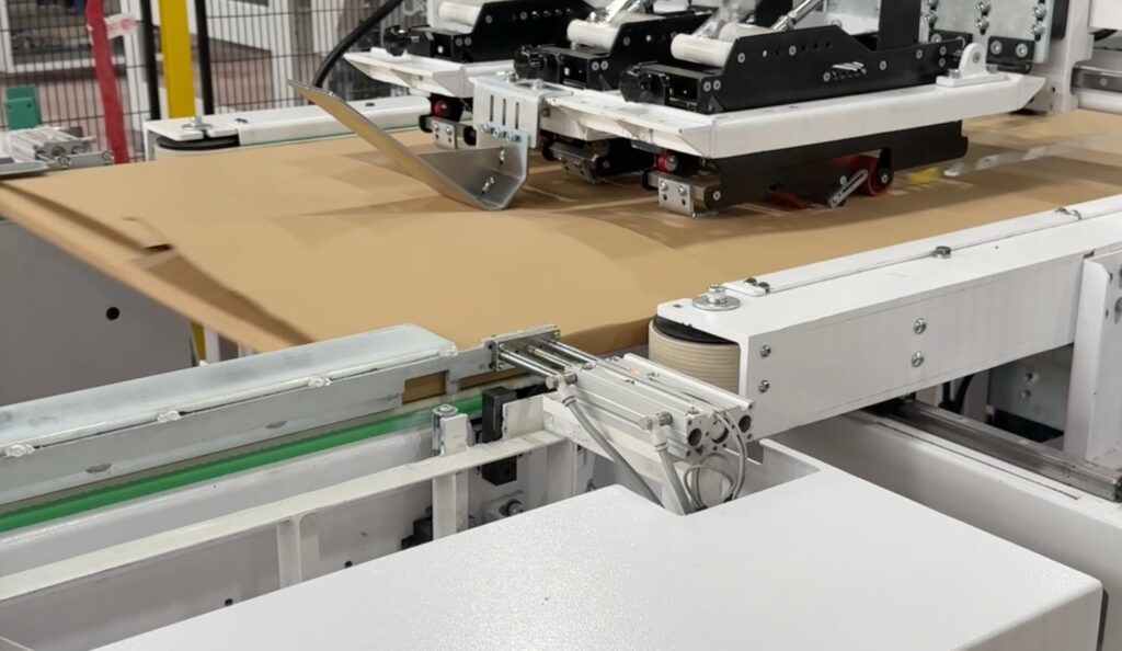 The advanced 3-line taping feature of Edda Lotis applying simultaneous secure center and edge tape lines on a wide flatpack carton.
